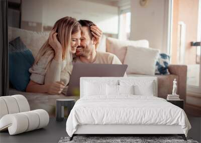 Beautiful young couple using laptop Wall mural