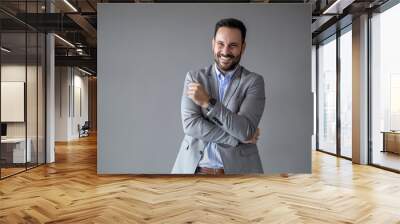 Portrait of a young businessman wearing grey suit on grey background Wall mural