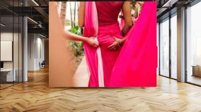 Bridesmaids grab Indian bride's hips walking around the garden Wall mural