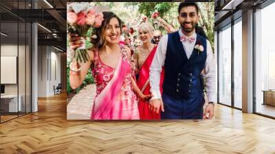 bridesmaids hold their bouquets up while bride and pose in the garden Wall mural