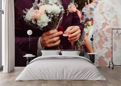 groom in wine jacket holds pastel bouquet and box with wedding r Wall mural