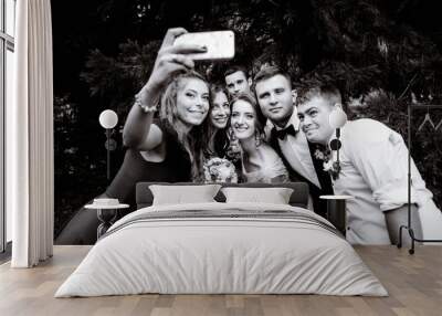 happy and young newlyweds and their bridesmaids making a photo Wall mural