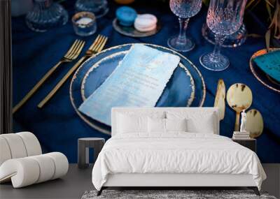 Menu card lies on a blue plate surrounded with golden dinner set Wall mural