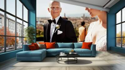 Smiling bald-headed groom looks at gorgeous bride with shiny whi Wall mural