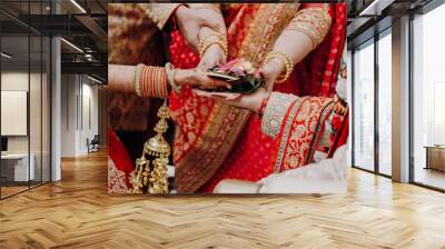 Tender hands of an Indian bride covered with henna tattoo hold groom's hands during the Septapadi ceremony Wall mural