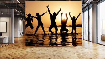 Silhouette of kids jumping on the beach Wall mural