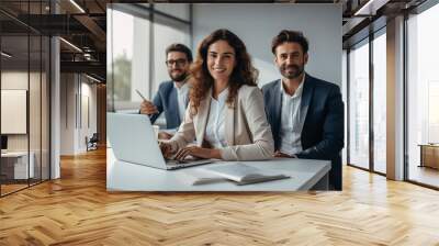 Business portrait of three people - two men and woman in suits, work team, smiling and sitting the office desk with laptop Wall mural