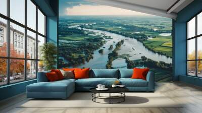 High-angle shot of a river overflowing its banks and flooding nearby farmlands.Aerial view of a river surrounded by lush trees and grass Wall mural