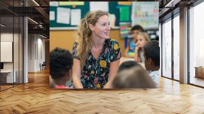 Teacher engaging with students in a lively classroom.A woman sits in front of a group of children in a classroom Wall mural