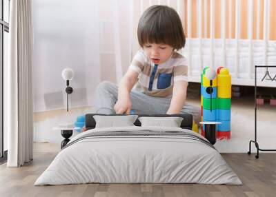 cute 2 years boy plays plastic blocks at home Wall mural