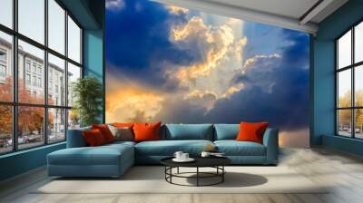 Clouds and a blue sky with a sunbeam shining through, evening time. Wall mural