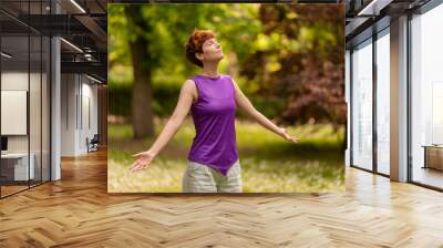 Androgynous woman enjoying fresh air in park Wall mural