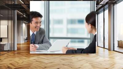 Business meeting in a modern office setting with two professionals discussing ideas and collaborating on a project during the daytime Wall mural