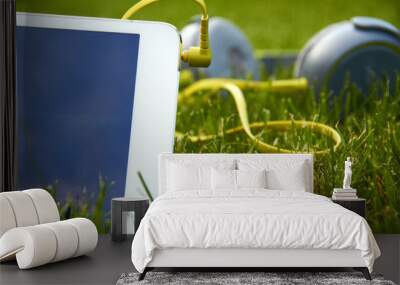 white tablet and headphones lying on the grass Wall mural