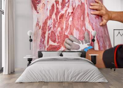 professional butcher in metal glove in factory refrigeration pushes meat with a bull carcass into cutting. The production of meat products. Wall mural