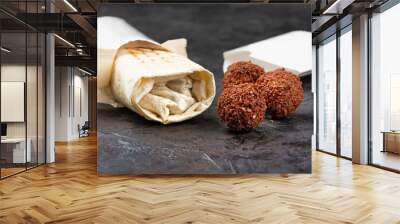 traditional oriental shawarma with fried falafel cutlets on a black background. Healthy snacks or takeaway lunch. concept of eco-packages for recyclable materials. Wall mural