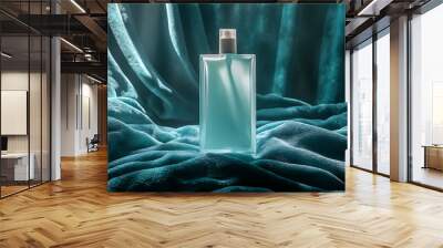 A glass bottle of perfume sits on a soft blue velvet fabric. The bottle is clear and the liquid inside is blue. Wall mural