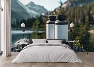 Two black supplement bottles with white labels sit on a rock in front of a beautiful mountain lake. Wall mural