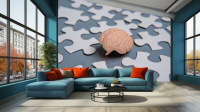 A close-up model of a human brain surrounded by scattered puzzle pieces. Wall mural