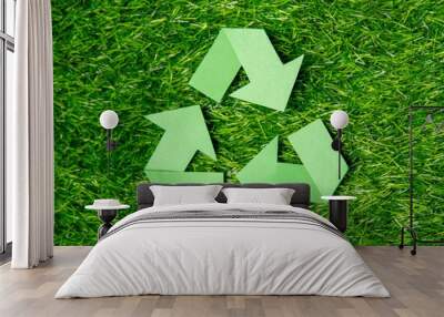 A green recycling symbol on a lush grass background with copy space. Environmental conservation and the importance of recycling concept. Wall mural