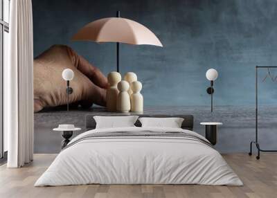 Umbrella and wooden dolls with copy space. Family protection and insurance coverage concept. Wall mural