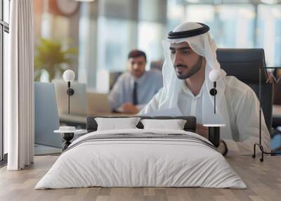 A young handsome Middle eastern Arab man was working on document in his office, looking at a laptop, talking on a video call, bill and agreement in hand Wall mural