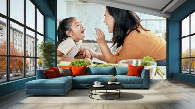 Health, eating and food with mother cooking in kitchen with nutrition, vegetables and care. Home, lunch and healthy diet of asian family with young daughter tasting green veggies with mom. Wall mural