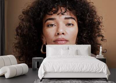 Makeup, confident and portrait of a woman with hair care, skincare and beauty against a brown studio background. Face, cosmetic and young girl model with a curly afro, cosmetics and empowerment Wall mural