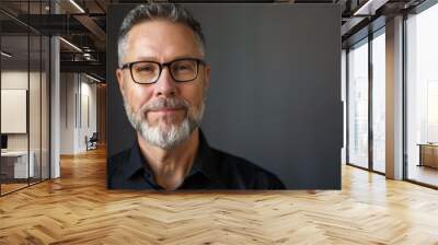 Confident Middle-Aged Man with Glasses Smiling Against a Dark Background Wall mural