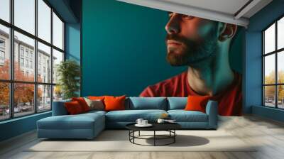 Side profile of a contemplative man with a beard, red shirt, and a moody blue light on the face Wall mural