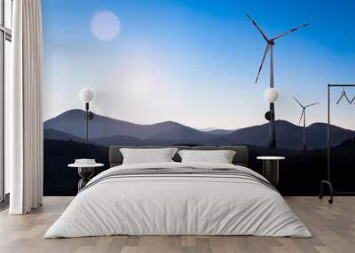 two wind turbines under blue sky in a landscape with hills Wall mural