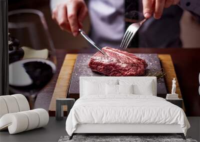 sirloin steak on a very hot stone being cooked by a man to his own taste on a wooden table with a knife and fork Wall mural