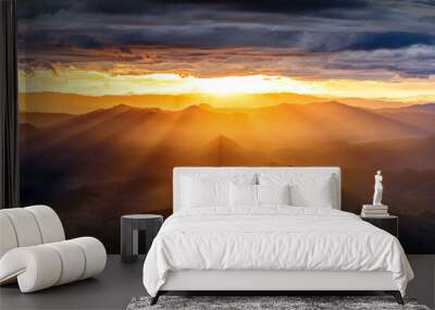 amazing dramatic cloudscape in sunset with sun rays over misty mountains landscape Wall mural