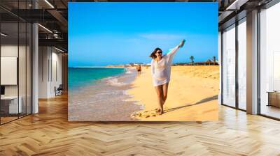 Beautiful woman walking on sunny beach Santa Maria, Sal Island, Cape Verde
 Wall mural