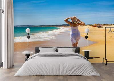 Beautiful woman walking on sunny beach
 Wall mural