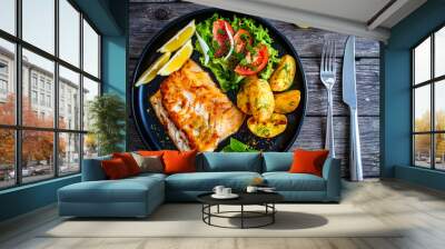 Fish dish - fried cod fillet with potatoes and vegetable salad on wooden table
 Wall mural