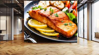 Fried salmon steak with potatoes and vegetables on wooden table Wall mural