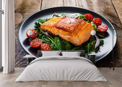 Fried salmon steak with vegetables on wooden table Wall mural