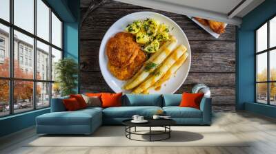 Fried schnitzel and white boiled asparagus with potato served on wooden table
 Wall mural