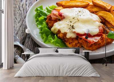 Milanesa Napolitana - fried breaded cutlet with ham, mozzarella cheese and tomato sauce on wooden background Wall mural