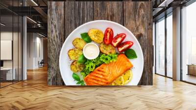 Seared salmon steak with baked potatoes and fresh vegetable salad served on wooden table
 Wall mural