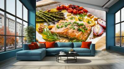 Sheet pan dinner - roasted salmon steak with asparagus, lemon ,rosemary, tomatoes, onion and garlic on cooking pan on wooden table
 Wall mural