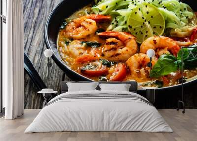 Tom Yam Kung soup - Thai soup with shrimps and rice noodles served in black bowl with chopsticks on wooden table
 Wall mural