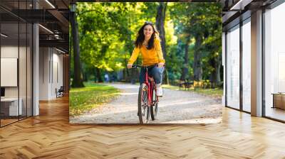 Urban biking - woman riding bike in city park Wall mural