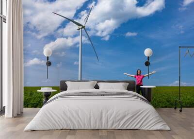 Woman standing near wind turbine on green meadow Wall mural