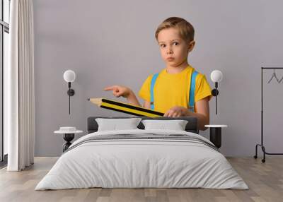 Little boy with a big pencil ready for school and study. Concept of education and learning. Wall mural