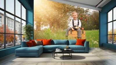 Smiling little boy with apples in an autumn orchard. Wall mural