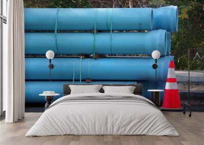 Blue plastic pipes for main water line construction stacked on a city street with a warning traffic cone Wall mural