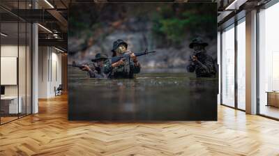 Soldiers with gun are walking along the river. War, soldier army, gun and hostage rescue concept. Wall mural