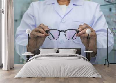 Close up optician holding eyeglasses frame in eyewear shop Wall mural